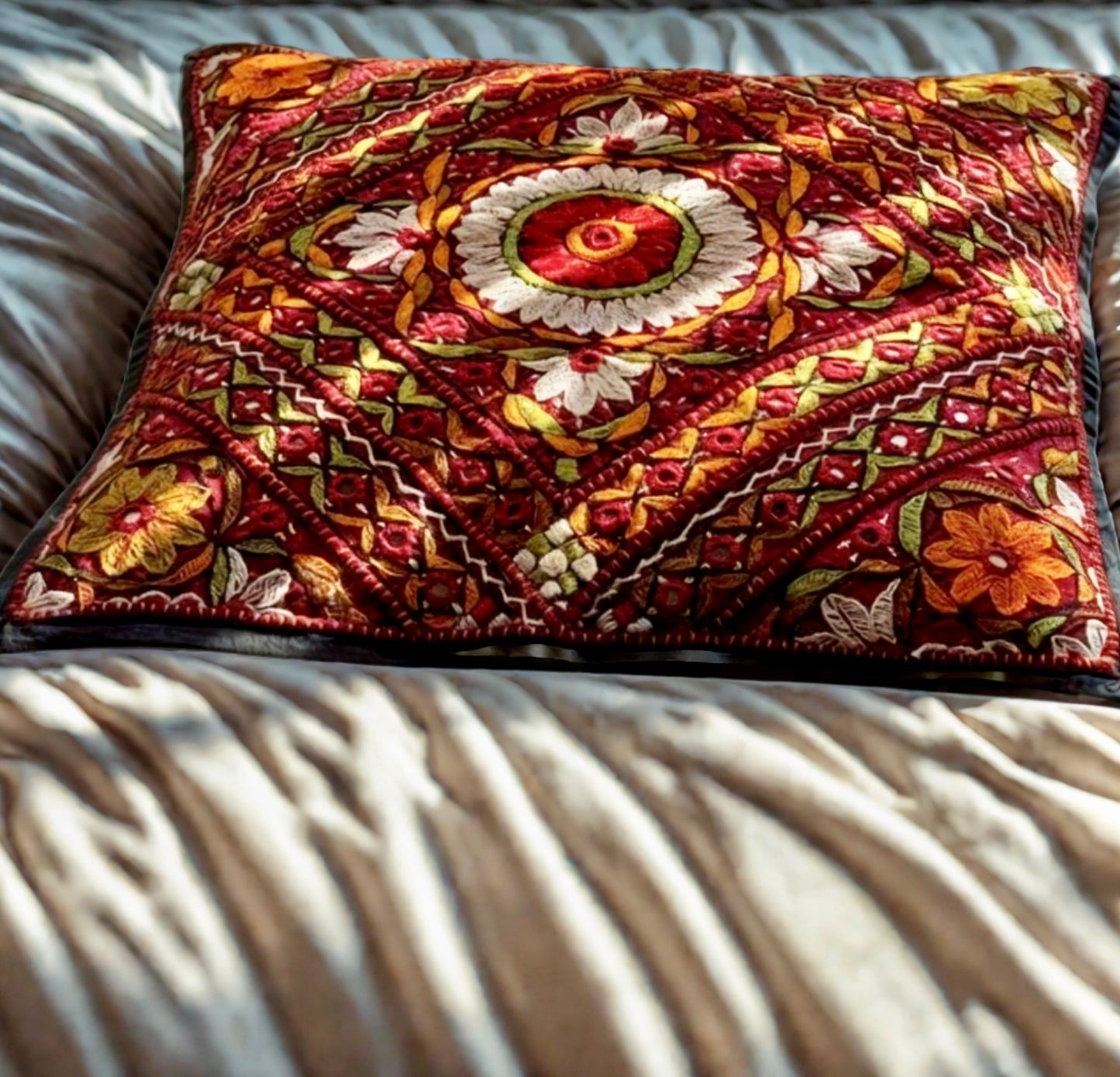 Cushion cover featuring vibrant Kutchi embroidery with intricate mirror work and colorful thread patterns on a textured fabric.